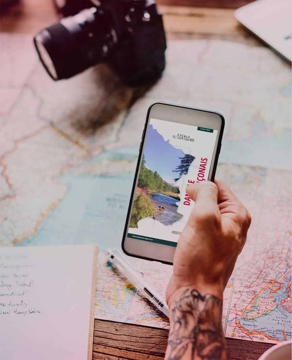 Un homme organise son prochain voyage en France en consultant un guide de voyage Escale Beauregard sur smartphone