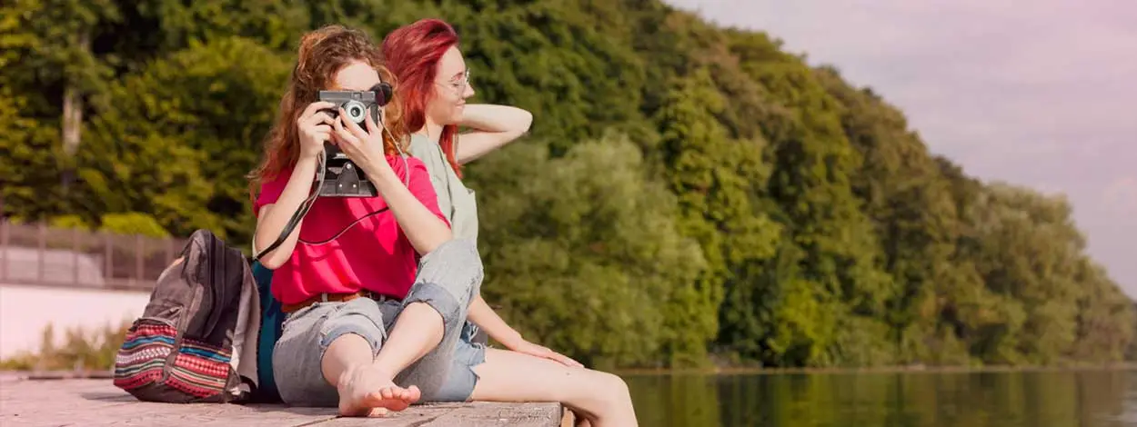 Jeunes femmes assises sur un ponton qui prennent le temps de profiter du paysage les pieds dans l'eau