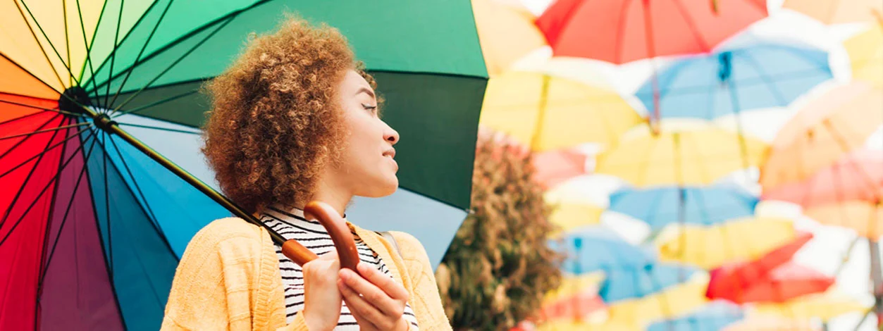 Jeune femme en voyage sous un parapluie coloré.